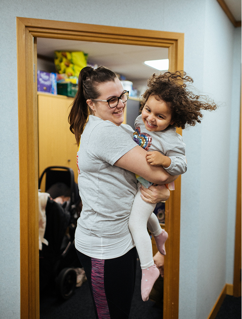 A woman holding a baby and smiling
