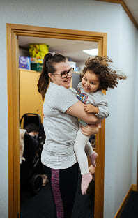 A woman holding a young child, smiling