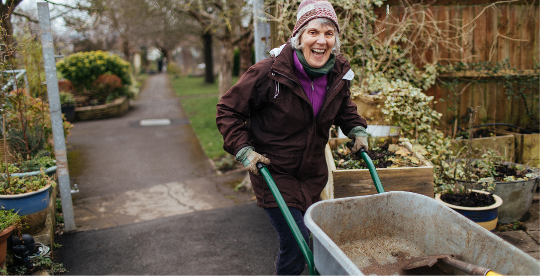 A woman with a wheelbarrow walking through a garden