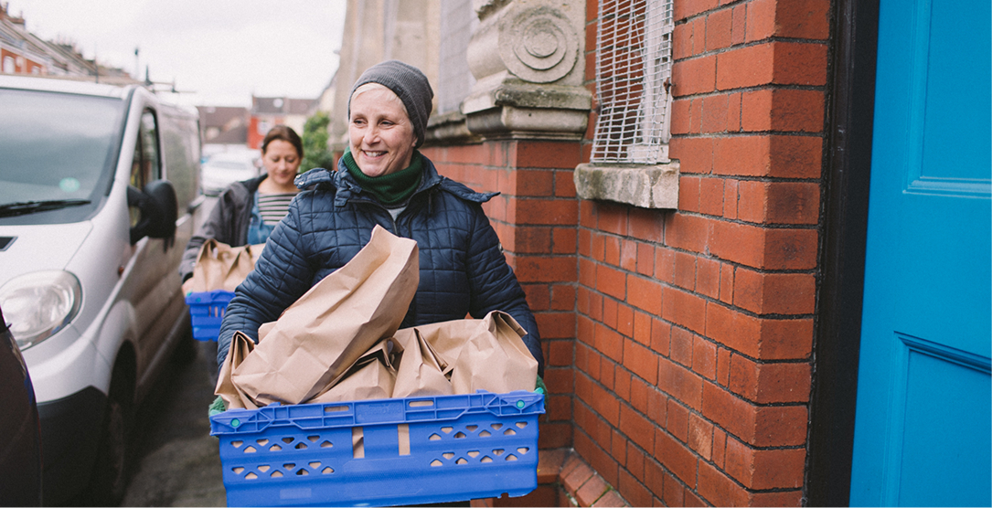 A woman carrying a large box of donated food items