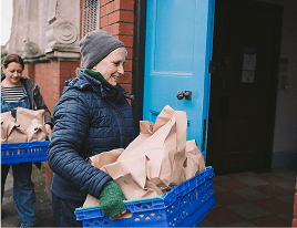 A woman carrying a container full of donated food items